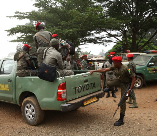 Gendarmerie officers climb a patrol vehicle ahead of an operation in Muyuka.