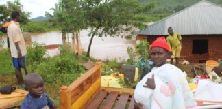 Woman outside a flood submerged house.