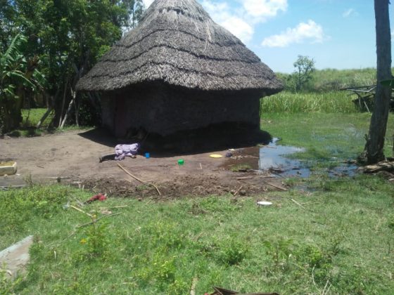 Child sleeps outside a flooded house.